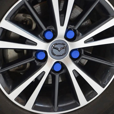 Close-up of a car wheel with blue lug covers and a Mazda emblem, showing design and color elements.