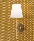 Wall sconce lamp with white shade on Certified Brown Floral Wallpaper With Glittering Gold Metallic Texture.