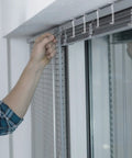 A hand adjusting Clear 20 Pack Valance Clips for Horizontal Blinds, demonstrating easy installation on window treatments.