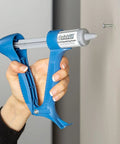 Hand using Drywall Repair Kit With Built In Spatula Tool And Two 20ml Spackling Paste Cartridges To Fill Nail Holes And Cracks
