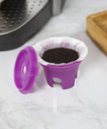 Open purple K-Cup pod with Disposable Paper Filters For Reusable K Cup Pods That Give You A Smoother Cleaner Brew No Mess Fits All Brands