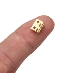 20 Pack Mini Cabinet Door Hinges For Dollhouses And Small Wooden Boxes shown on fingertip for scale.