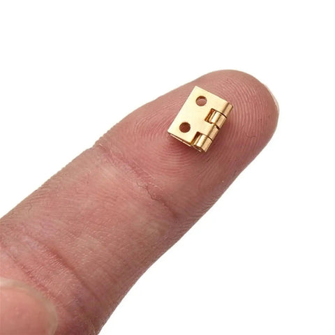 20 Pack Mini Cabinet Door Hinges For Dollhouses And Small Wooden Boxes shown on fingertip for scale.