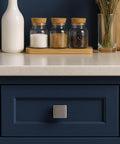 Square Brushed Satin Nickel Cabinet Knobs 10 Pack One And One Eighth Inch For Kitchen Cabinets And Furniture Single Hole Zinc Alloy Pulls Dressers Wardrobe Bathroom Closet Handles By EAXINTA installed on a dark blue drawer in a kitchen setting.