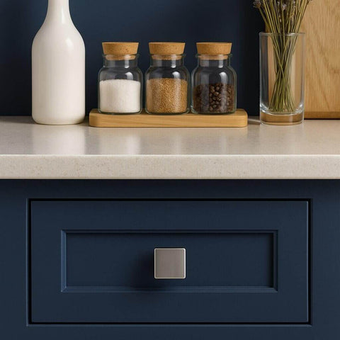 Square Brushed Satin Nickel Cabinet Knobs 10 Pack One And One Eighth Inch For Kitchen Cabinets And Furniture Single Hole Zinc Alloy Pulls Dressers Wardrobe Bathroom Closet Handles By EAXINTA installed on a dark blue drawer in a kitchen setting.