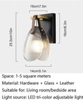Fluted Glass Wall Sconce Ribbed Shade Leather Strap Brass Finish Metal Light 10 Inch Height mounted on wall with adjustable lighting for home use.