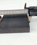 Pro Grade Graphite Ingot Block For EDM Milling Surface 99.9% Purity 100 By 100 By 20 Mm Black being measured with calipers
