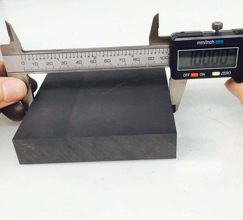 Pro Grade Graphite Ingot Block For EDM Milling Surface 99.9% Purity 100 By 100 By 20 Mm Black being measured with calipers