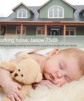 Sleeping baby with teddy bear, noise level below 75dB, in front of green house, enhancing healthy working environment.
