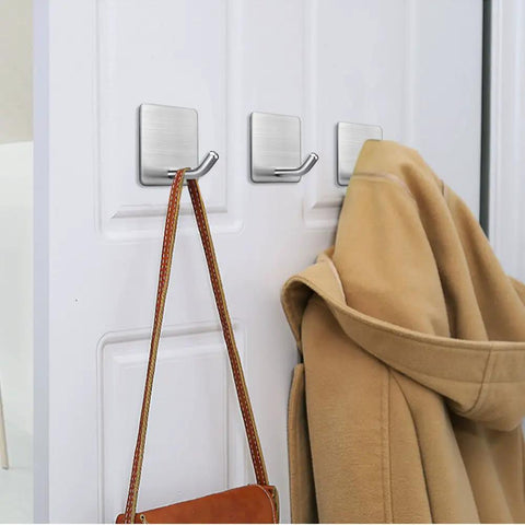 Adhesive Stainless Steel Wall Hooks 4 Pack Heavy Duty Waterproof Stick On Mount For Towels Coats Hats Robes Bags And More Bathroom Kitchen Mounts No Drill Easy Install showing hooks holding coat and bag on white door
