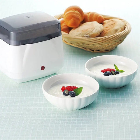 Dead Simple Compact Automatic Yogurt Maker With Food Grade Stainless Inner Pot And 360 Even Radiant Warmth For Smooth Homemade Dairy Culturing Right In Your Kitchen next to two bowls of yogurt topped with berries.