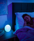 Bedroom scene with woman sleeping and Smart Led Entertainment Lamp And Night Light With 16 Million Colors on nightstand.