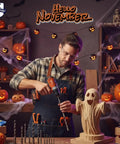 Man in workshop using drill surrounded by Halloween decorations, including carved pumpkins and ghost sculpture.