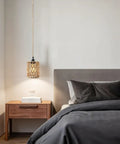Amp Up Your Space With This Straight Up Badass Boho Pendant Light Featuring A Heavy Duty 16.5 Ft Plug In Swag Cord And Handwoven Rattan Cylinder Shade For Zero Hassle Setup And Chill Room Vibes, hanging over a bedside table.