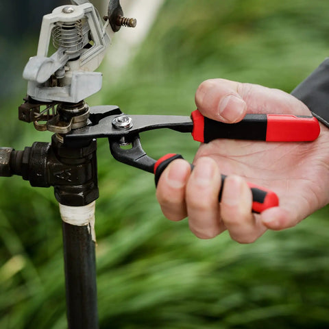 Person using 6.5 Inch Slip Joint Pliers with Groove Joint Function on a pipe valve, showcasing ergonomic grip and heavy duty use.