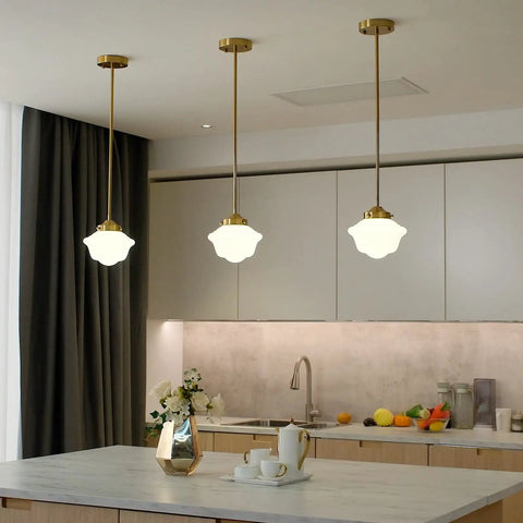 Elegant kitchen with three brass pendant lights hanging over island