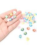 Hand holding assorted 12mm Frangipani Flower Beads Set 50Pcs 12mm Polymer Clay Plumeria Floral Beads with holes for DIY crafts.