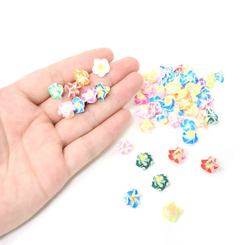 Hand holding assorted 12mm Frangipani Flower Beads Set 50Pcs 12mm Polymer Clay Plumeria Floral Beads with holes for DIY crafts.