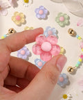 Hand holding a pink pastel jelly daisy charm from the Pastel Jelly Daisy Flower Shoe Charms Set With Glossy Bling Floral Buckles.