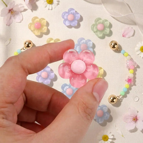 Hand holding a pink pastel jelly daisy charm from the Pastel Jelly Daisy Flower Shoe Charms Set With Glossy Bling Floral Buckles.
