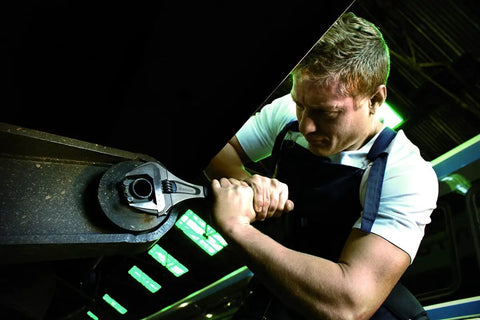 Man using Ergo Extra Wide Adjustable Wrench 12 Inch with Slim Head and Extra Wide Jaw for tight spots under machinery.