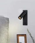 Modern Rotatable Cylinder Wall Sconce Wall Mount Reading Spotlight beside a sofa on a wall, black finish, adjustable lighting.