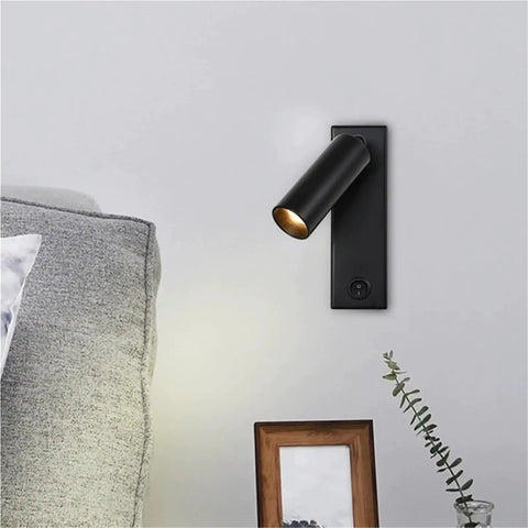 Modern Rotatable Cylinder Wall Sconce Wall Mount Reading Spotlight beside a sofa on a wall, black finish, adjustable lighting.