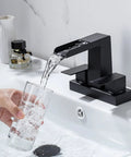 4 Inch Centerset Waterfall Bathroom Faucet With Two Handles, 3 Hole Basin Setup, Pop Up Drain With Overflow in use pouring water into a glass