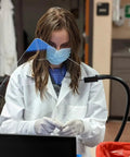Person using Heavy-Duty Flexible Arm Safety Shield With Magnetic Base, 18-Inch Reach, 10x10 Inch Shield, in lab setting.