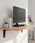 Heavy Duty Triangular Wall Bracket For Floating Desks And Shelves In Black Or White Finish Built With Q235 Steel For Rock Solid Support Of Monitors Books And Gear Easy Wall Mount 1 Pack supporting a wooden shelf with monitor