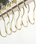 Gold Stainless Steel Shower Curtain Rings 24 Pack With Five Bead Gourd Design Smooth Glide Hooks on rod close-up.