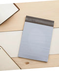 Waterproof Poly Mailer Bags 10x14 Inches White Self Seal Envelopes on wooden desk with notebooks