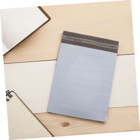 Waterproof Poly Mailer Bags 10x14 Inches White Self Seal Envelopes on wooden desk with notebooks