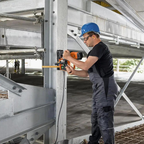 Heavy Duty Magnetic Base Drill Built Tough For One Quarter Inch Steel Cuts in use on metal structure with worker.