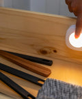 Tap On Off LED Light Stick-On Battery Powered Wireless Portable Light for cabinets, illuminating utensils in a drawer.
