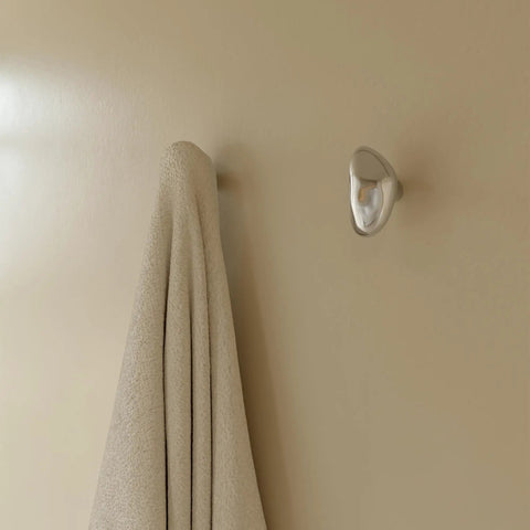 Sweet Looking Pebble Wall Hook Built From Top Shelf 304 Stainless Steel holding a towel on a light beige wall.