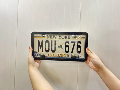 Person holding New York plate with Clear License Plate Frame Protectors 2 Pack Universal Fit For All US Standard Plates.