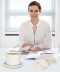 Smiling woman at desk with 6 Pack White Marble Coaster Set With Holder, Absorbent Ceramic Drink Coasters For Bar And Coffee Table, Cute Modern Cork Non Slip Desk Decor, Totally Cool Gift Idea For Home Or Office, Stone Style Coasters