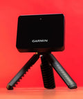 Portable Golf Launch Monitor And Simulator Bundle with tripod on red background, includes 10 hour battery, case, charger, adapter.