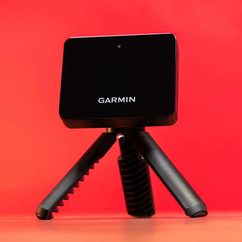 Portable Golf Launch Monitor And Simulator Bundle with tripod on red background, includes 10 hour battery, case, charger, adapter.