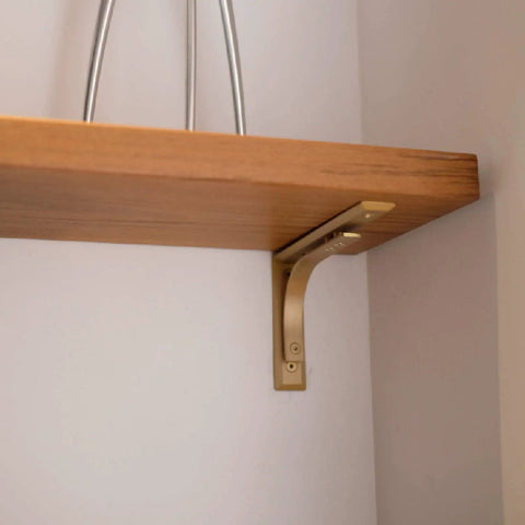 Heavy Duty Shelf Brackets Wall Mount Kickass Brass Metal Supports installed under a wooden shelf holding it securely.