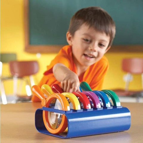 Child in classroom using Six Jumbo Science Magnifiers With Stand For Kids Ages 3 Plus, durable plastic lenses, easy grip design.