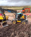 Excavator on construction site with bucket attachment, showcasing versatility of Fast Swap Quick Hitch For Mini Excavators And Backhoes