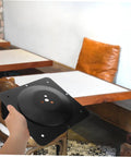 Heavy Duty Table Leg Mounting Plate And Rock Solid Fixing Bracket For Wobbly Furniture Repair Sofa Attachment No Sweat Install Top Shelf DIY Hardware Kit held in hand, black steel plate for furniture support.