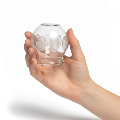 Hand holding Deluxe 4 Piece Glass Cupping Set With Fire Cupping Jars Vacuum Therapy 4 Sizes And Handy Finger Grips Professional Grade Massage Tools