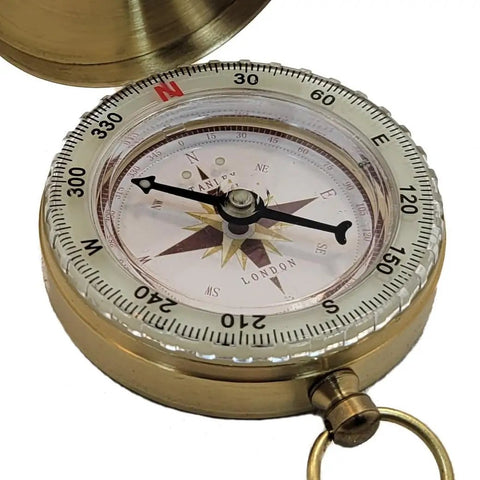 Close-up of the Glow In The Dark Brass Pocket Compass for Kids, open to reveal its luminous dial and brass housing.