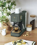 Rock Solid Compact Espresso Machine In Fresh Thyme Green with 20 bar pump brewing coffee on kitchen countertop.