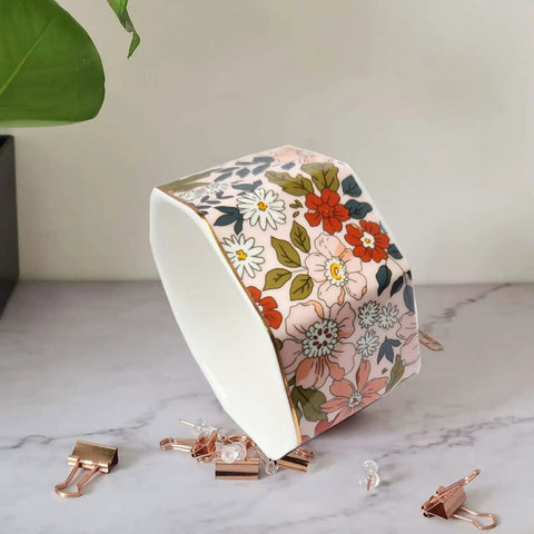 Ceramic Paper Clip Holder With Gold Line Dispenser, floral pink design, holding paper and binder clips on desk.