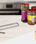 All In One Adjustable Jar And Can Opener No Fuss Stainless Steel Manual Kitchen Gadget with jars on a kitchen counter