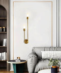 UPRENXIAO Modern Wall Sconce Linear Curved Design Up Down Lighting Ambient(Gold) on a white wall beside a gray sofa.